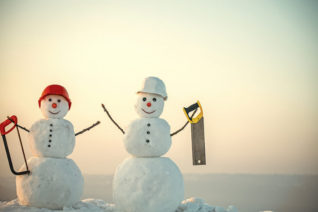 Two cool construction snowmen with hard hats and saws.